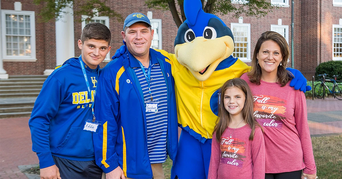 A family poses for a photo with YoUDee
